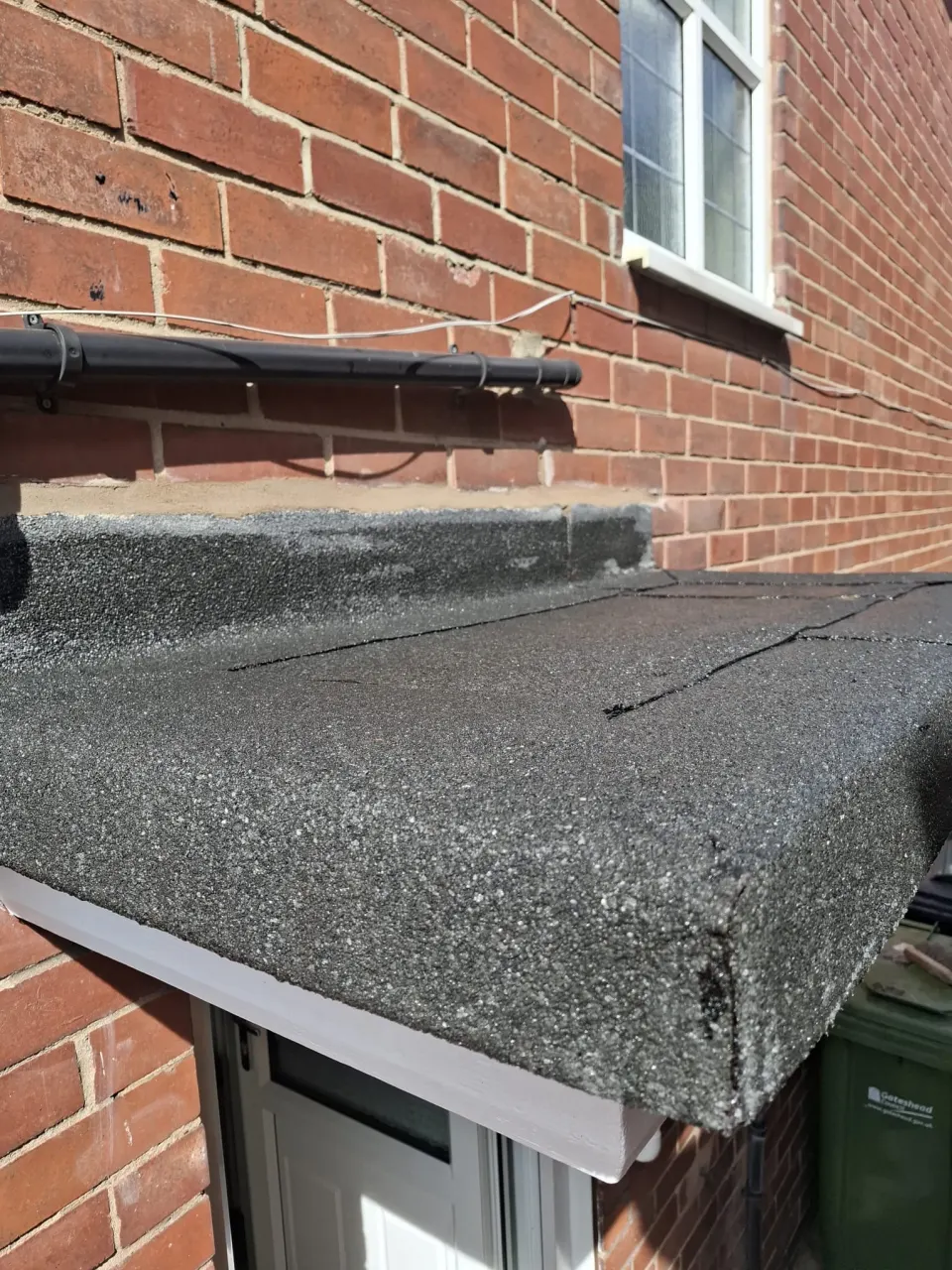 Cracked, failing felt roof on a porch canopy before replacement