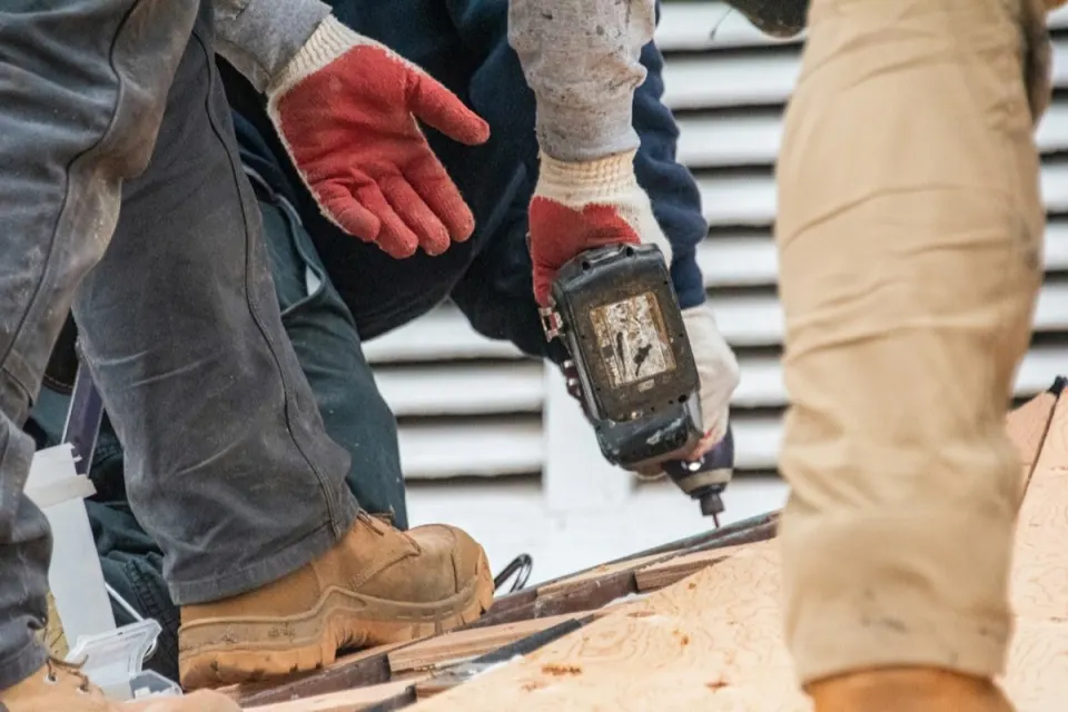Roofer carrying out a flat roof repair, securing the membrane